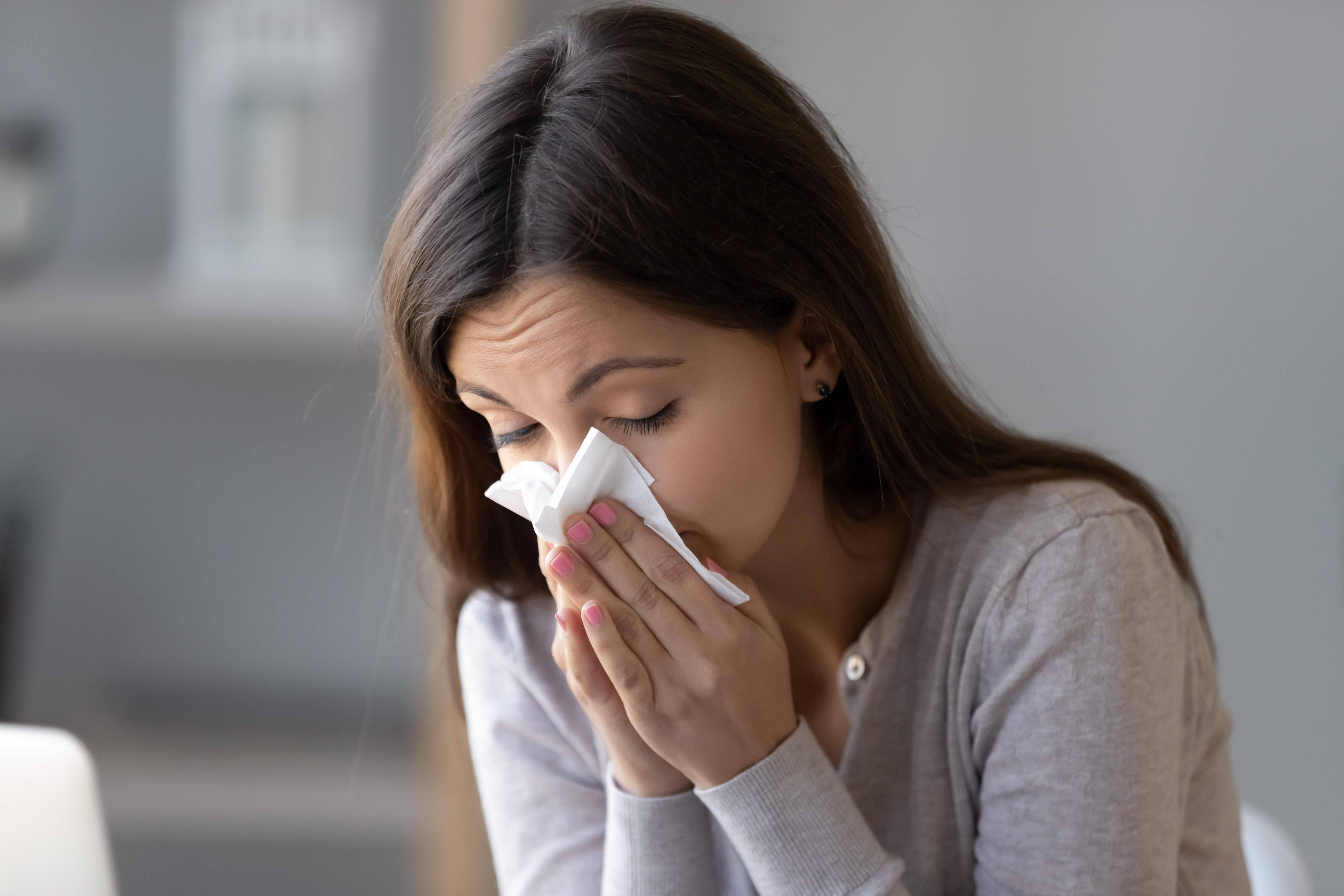 Woman blowing her nose due to sinus congestion